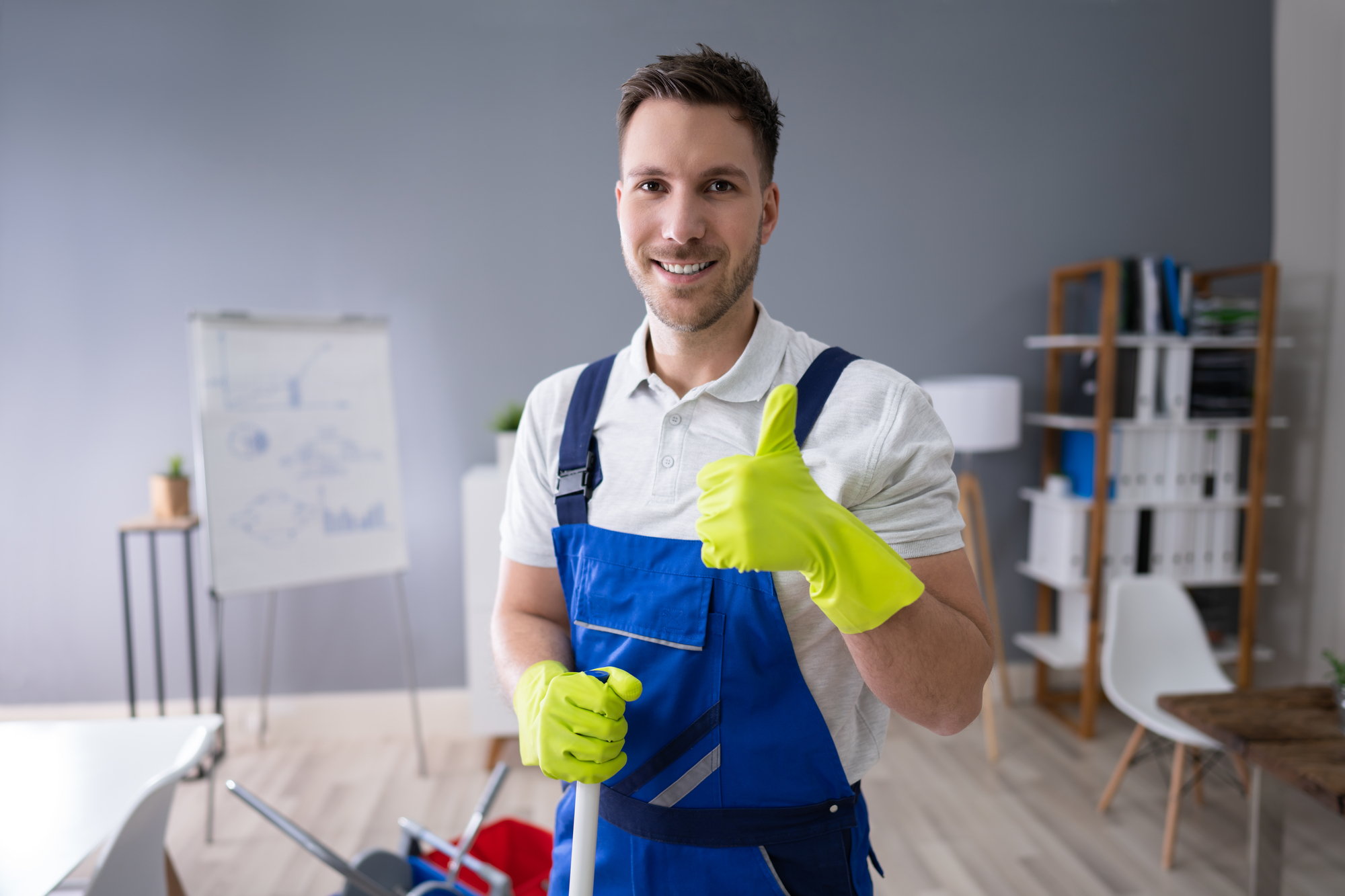 Full Length Portrait Of Happy Male Worker With Broom Cleaning Office